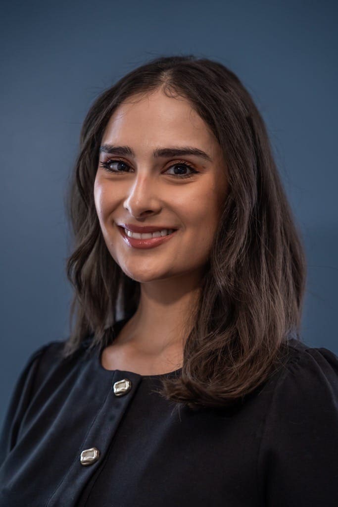 Diana Benzor, Head of Client Success, standing against blue background.