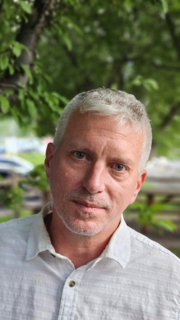 Casey Cummins, Solution Consultant, standing in front of trees.