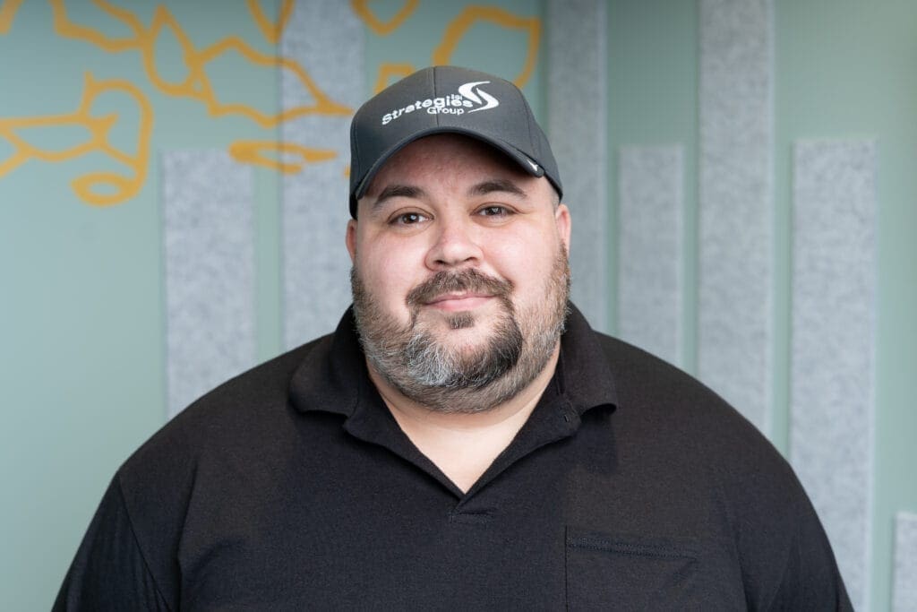 Joe Worthington, Support Specialist, standing in front of an office wall.